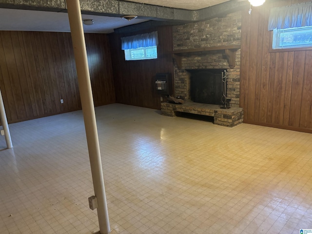 below grade area featuring wooden walls, heating unit, and a brick fireplace