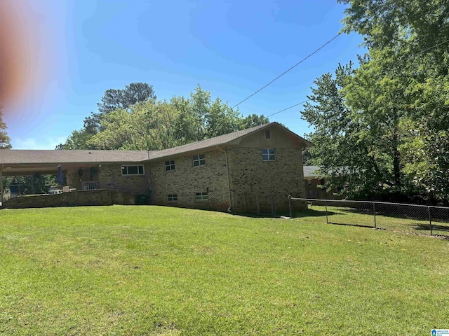 back of property with brick siding, a yard, and fence