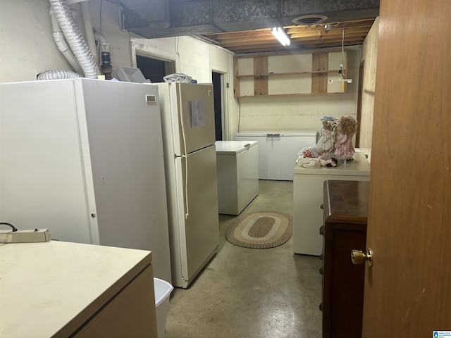kitchen with refrigerator, washer and clothes dryer, light countertops, and finished concrete floors
