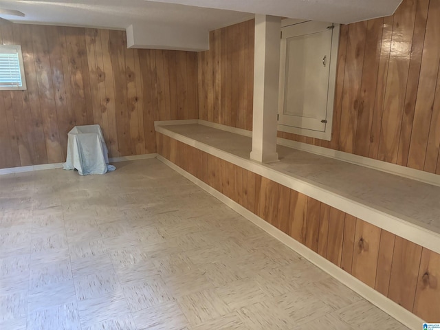 basement featuring baseboards and wood walls