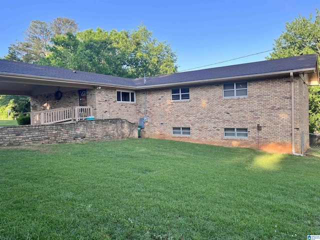 view of property exterior with brick siding, fence, and a lawn