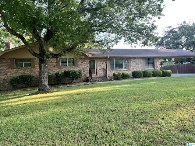 single story home with a front yard, fence, an attached carport, and brick siding