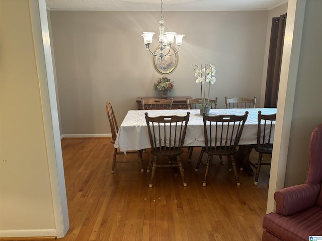 dining room with hardwood / wood-style floors, baseboards, an inviting chandelier, and crown molding