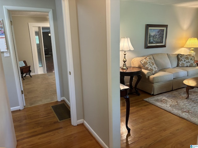 hallway with visible vents, wood finished floors, and baseboards