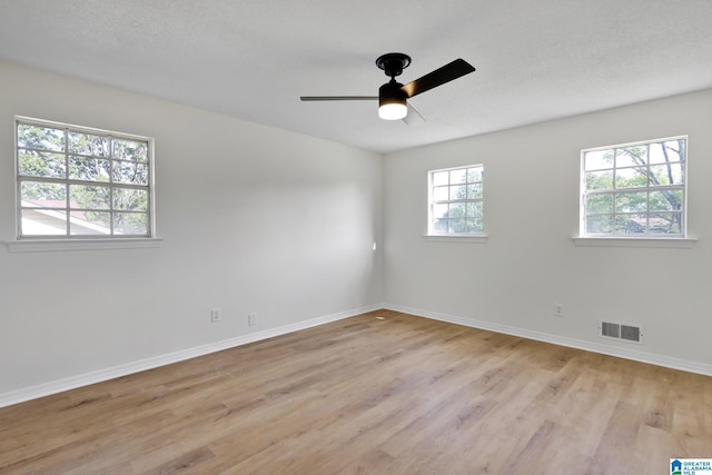 empty room featuring baseboards, visible vents, light wood-style floors, and ceiling fan