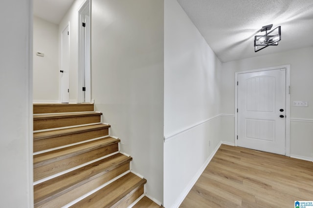 interior space featuring wood finished floors, a textured ceiling, and baseboards