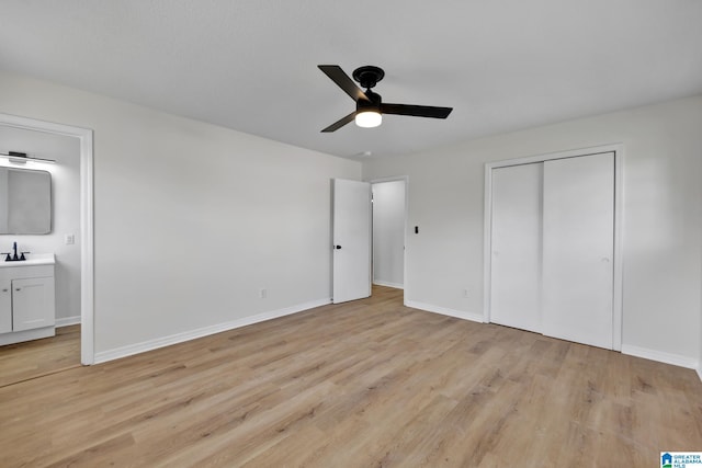 unfurnished bedroom featuring light wood finished floors, a sink, baseboards, a closet, and connected bathroom