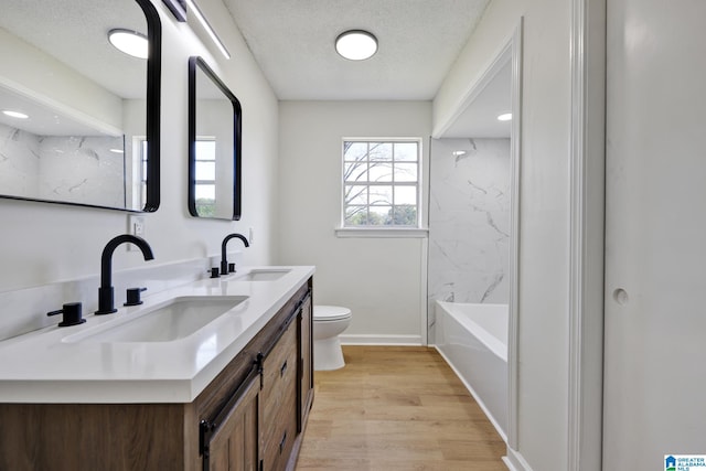 full bathroom featuring wood finished floors, a sink, a textured ceiling, and toilet