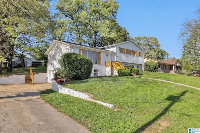 split level home with brick siding, an attached garage, driveway, and a front yard