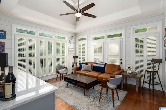 living room with light wood finished floors, a wealth of natural light, a ceiling fan, and a tray ceiling