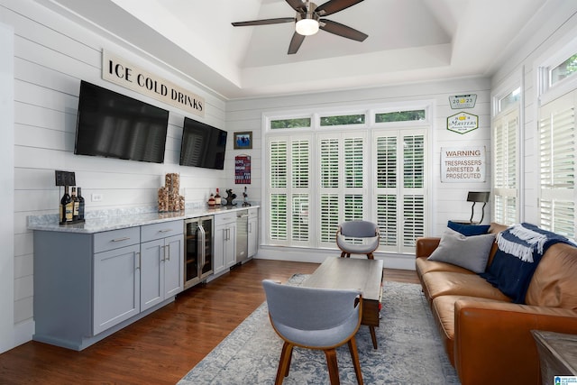 living room with beverage cooler, a raised ceiling, a ceiling fan, dark wood-type flooring, and a dry bar