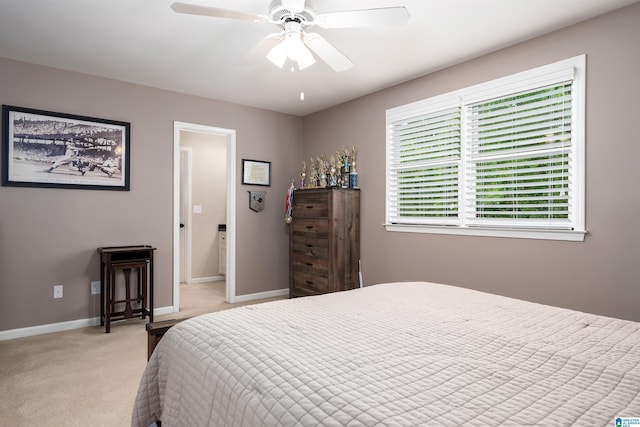 bedroom with light colored carpet, a ceiling fan, and baseboards