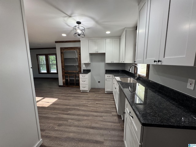 kitchen featuring recessed lighting, dark wood finished floors, a sink, dark stone counters, and white cabinetry