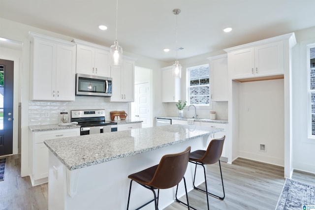 342 Shiloh Creek Dr, Calera, AL 35040 - kitchen with appliances with stainless steel finishes, a center island, white cabinetry, light wood finished floors, and recessed lighting
