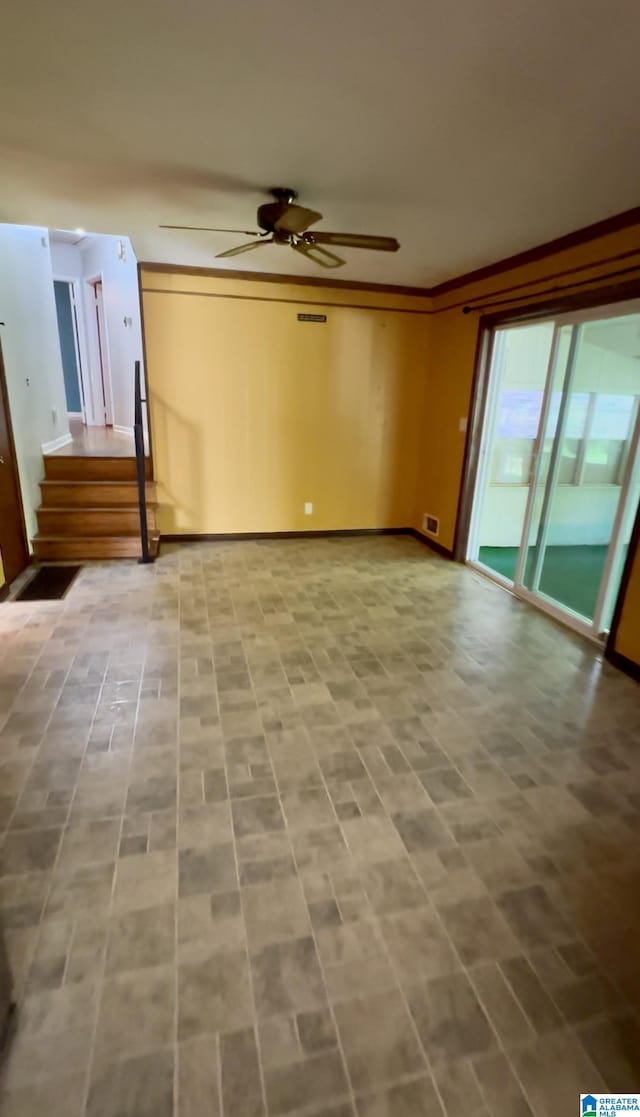 unfurnished living room featuring crown molding, visible vents, a ceiling fan, and stairs