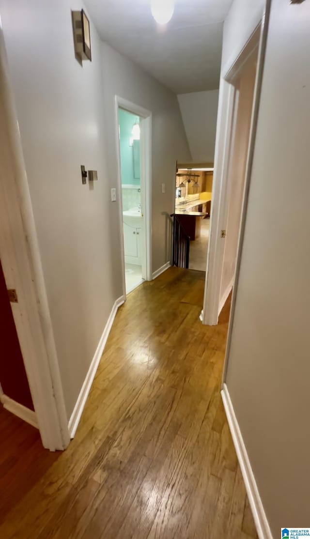 hall with vaulted ceiling, baseboards, and hardwood / wood-style floors