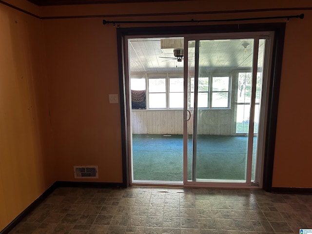 doorway with stone finish floor, visible vents, baseboards, and ceiling fan