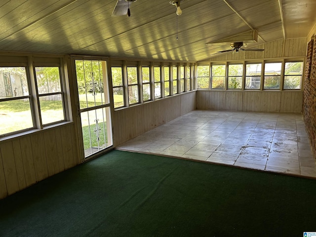unfurnished sunroom with a wealth of natural light, wood walls, and ceiling fan