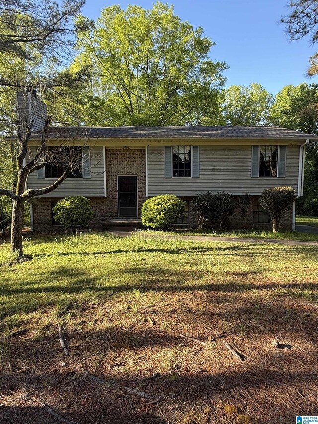 view of front of property featuring a chimney, brick siding, and a front yard