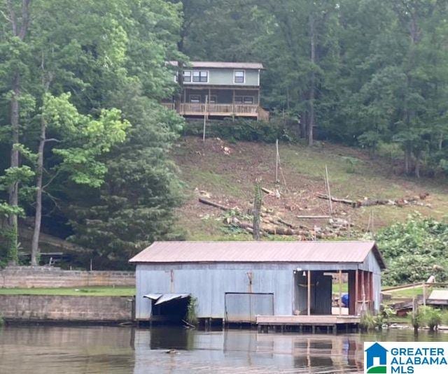 exterior space with a dock, a wooded view, and a water view