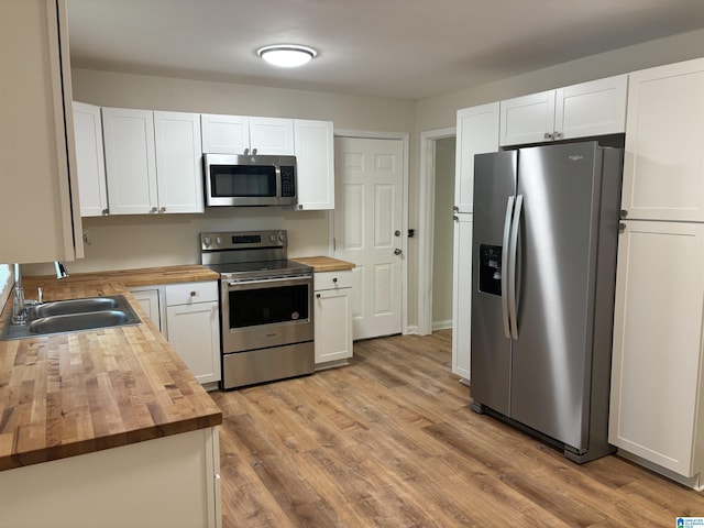 kitchen featuring a sink, wood counters, white cabinetry, light wood-style flooring, and appliances with stainless steel finishes