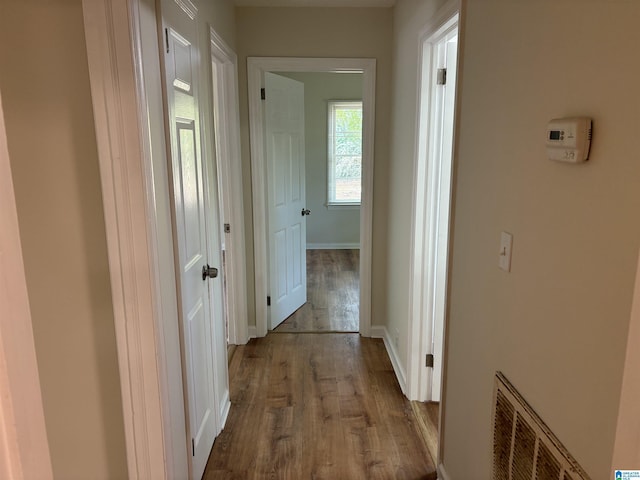 hallway with baseboards, visible vents, and dark wood-style flooring