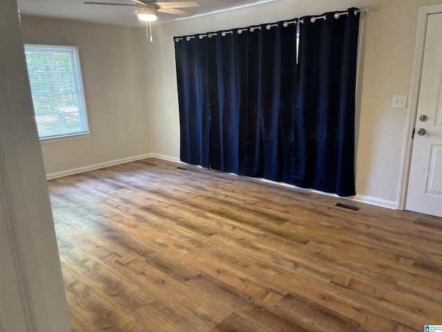 unfurnished room with visible vents, baseboards, a ceiling fan, and wood finished floors