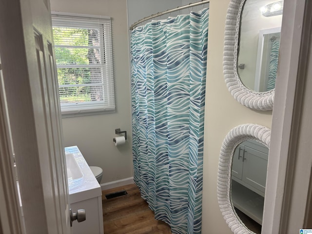 bathroom featuring a wealth of natural light, toilet, wood finished floors, and visible vents