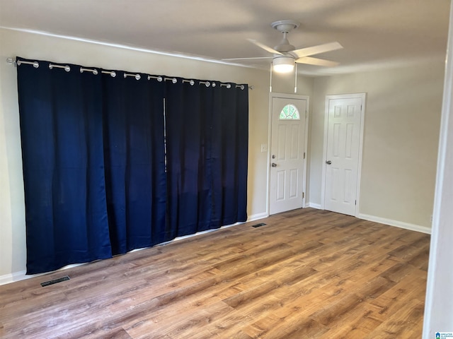 empty room featuring baseboards, a ceiling fan, wood finished floors, and visible vents