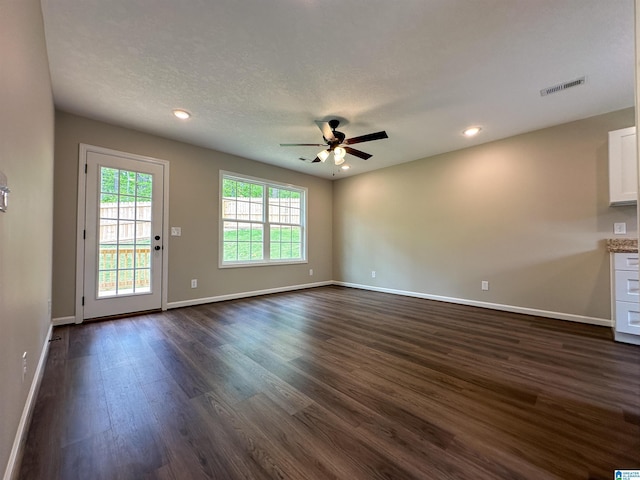 unfurnished living room with baseboards, visible vents, ceiling fan, and dark wood-style flooring