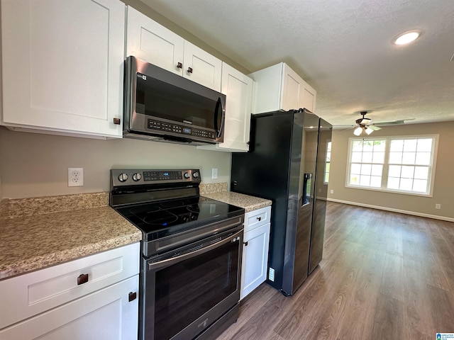 kitchen featuring white cabinets, dark wood-style floors, baseboards, ceiling fan, and appliances with stainless steel finishes