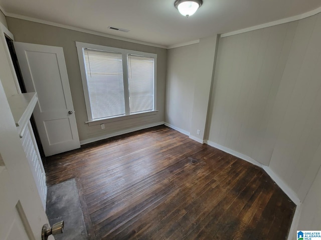 unfurnished dining area with visible vents, ornamental molding, baseboards, and dark wood-style flooring