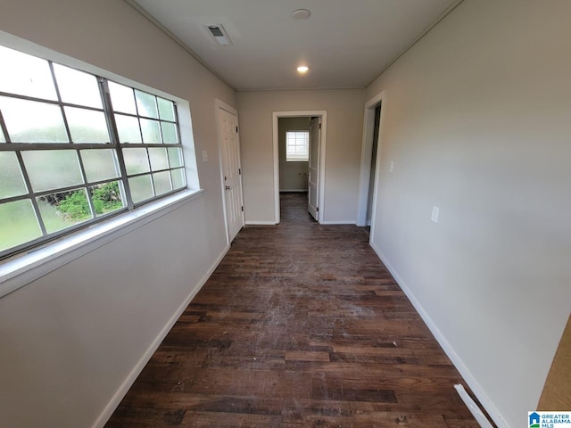 hall with visible vents, baseboards, and dark wood finished floors