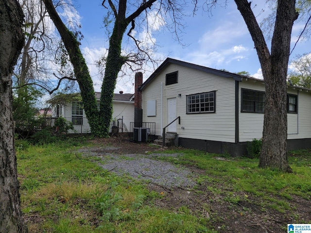 rear view of house featuring central air condition unit and a chimney