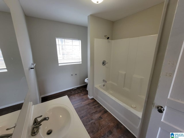 full bath with wood finished floors, a sink, bathtub / shower combination, baseboards, and toilet