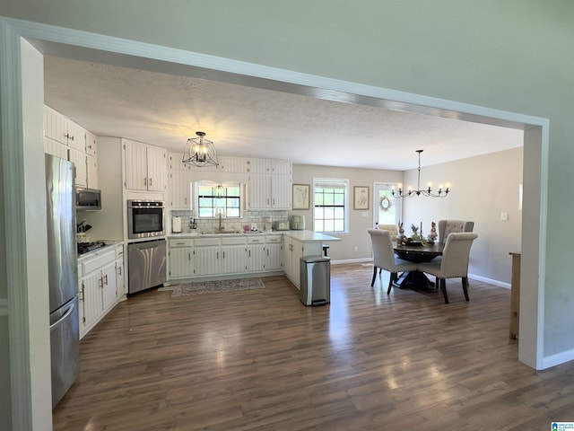 632 Bernard Couch Dr, Anniston, AL 36207 - kitchen featuring a sink, a chandelier, a peninsula, baseboards, and appliances with stainless steel finishes
