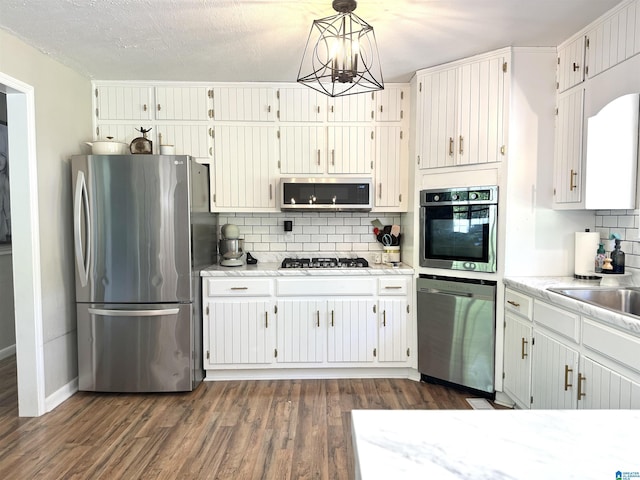 632 Bernard Couch Dr, Anniston, AL 36207 - kitchen with appliances with stainless steel finishes, dark wood-style flooring, tasteful backsplash, and a notable chandelier