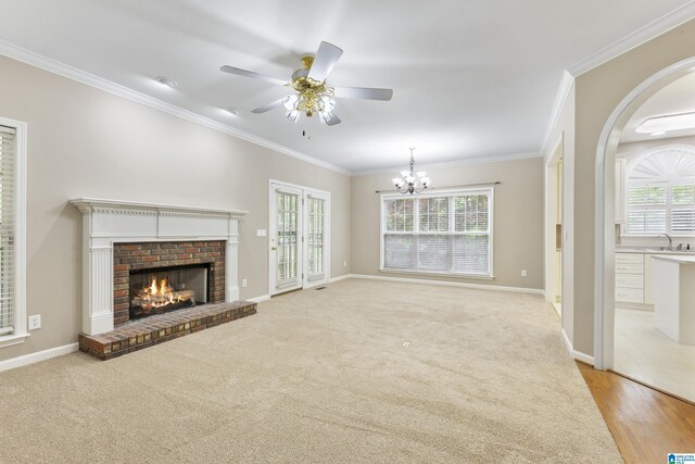 43 Dogwood Dr, Calera, AL 35040 - unfurnished living room featuring crown molding, a sink, a brick fireplace, ceiling fan with notable chandelier, and baseboards