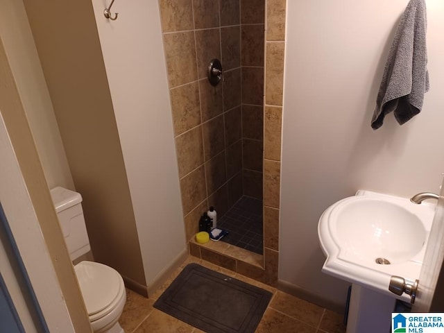 full bathroom with toilet, baseboards, tile patterned flooring, and tiled shower