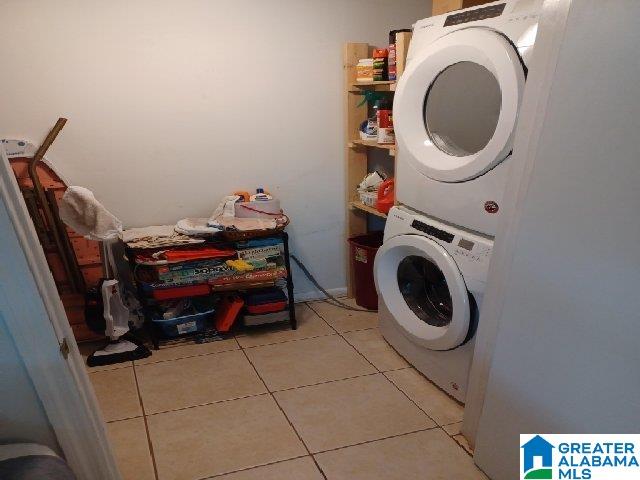 clothes washing area with stacked washer and clothes dryer, laundry area, and light tile patterned floors