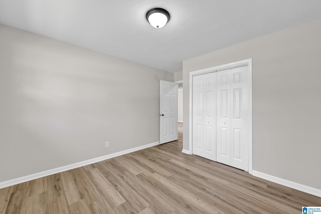 unfurnished bedroom featuring light wood-style flooring, a closet, and baseboards