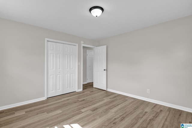unfurnished bedroom featuring baseboards, a closet, and light wood-type flooring