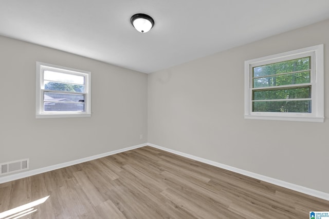spare room featuring baseboards, wood finished floors, and visible vents