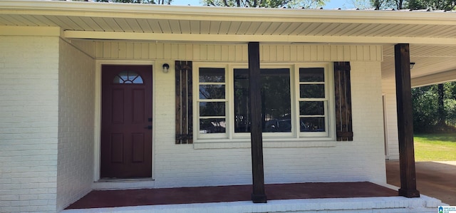 doorway to property with brick siding and a porch