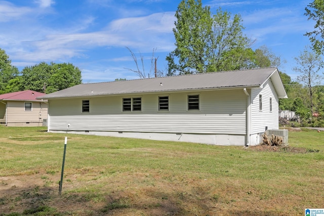 rear view of property with central AC unit, crawl space, a yard, and metal roof