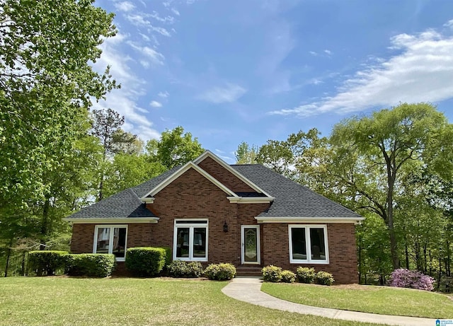craftsman inspired home with a shingled roof, brick siding, and a front yard