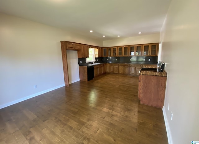kitchen with baseboards, dark countertops, dark wood-type flooring, and glass insert cabinets
