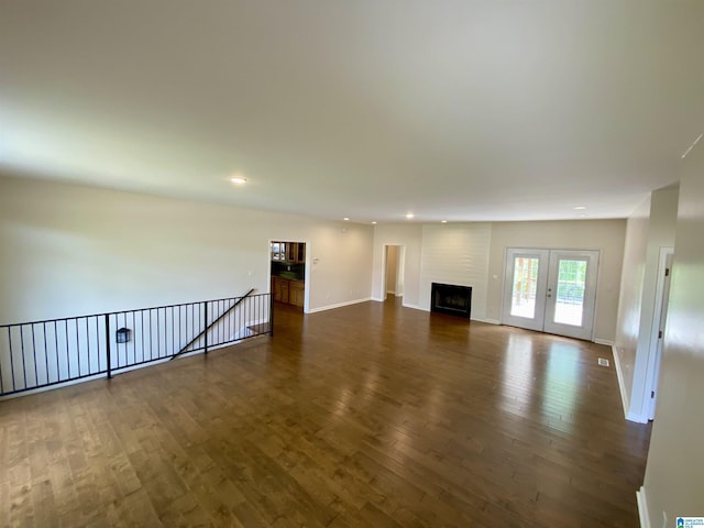 unfurnished living room with a large fireplace, baseboards, recessed lighting, and dark wood-type flooring
