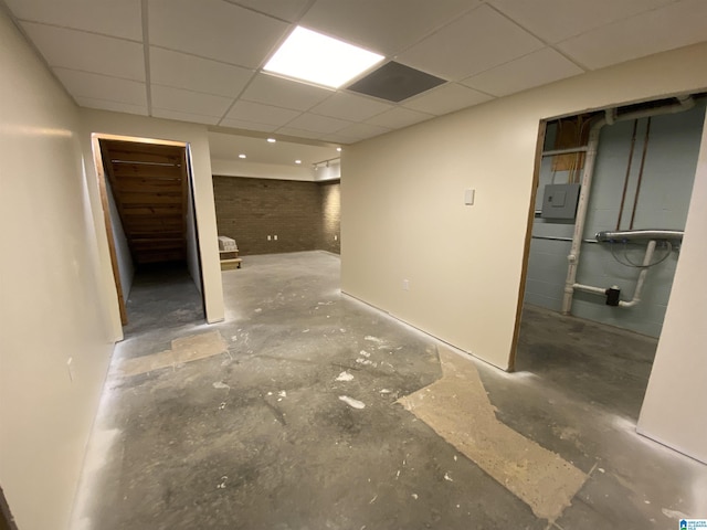 finished basement featuring stairway, electric panel, and a drop ceiling