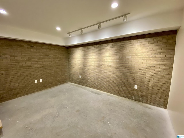below grade area featuring brick wall, track lighting, and recessed lighting